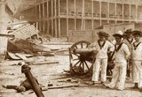 The Anglo-Zanzibar War was fought between the United Kingdom and the Zanzibar Sultanate on 27 August 1896. The conflict lasted around 40 minutes, and is the shortest war in history. The immediate cause of the war was the death of the pro-British Sultan Hamad bin Thuwaini on 25 August 1896 and the subsequent succession of Sultan Khalid bin Barghash. The British authorities preferred Hamud bin Muhammed, who was more favourable to British interests, as sultan. In accordance with a treaty signed in 1886, a condition for accession to the sultanate was that the candidate obtain the permission of the British consul, and Khalid had not fulfilled this requirement. The British considered this a casus belli and sent an ultimatum to Khalid demanding that he order his forces to stand down and leave the palace. In response, Khalid called up his palace guard and barricaded himself inside the palace.<br/><br/>

The ultimatum expired at 09:00 East Africa Time (EAT) on 27 August, by which time the British had gathered three cruisers, two gunboats, 150 marines and sailors, and 900 Zanzibaris in the harbour area. The Royal Navy contingent were under the command of Rear-Admiral Harry Rawson whilst their Zanzibaris were commanded by Brigadier-General Lloyd Mathews of the Zanzibar army (who was also the First Minister of Zanzibar). Around 2,800 Zanzibaris defended the palace; most were recruited from the civilian population, but they also included the sultan's palace guard and several hundred of his servants and slaves. The defenders had several artillery pieces and machine guns which were set in front of the palace sighted at the British ships. A bombardment which was opened at 09:02 set the palace on fire and disabled the defending artillery. A small naval action took place with the British sinking a Zanzibari royal yacht and two smaller vessels, and some shots were fired ineffectually at the pro-British Zanzibari troops as they approached the palace. The flag at the palace was shot down and fire ceased at 09:40.<br/><br/>

The sultan's forces sustained roughly 500 casualties, while only one British sailor was injured. Sultan Khalid received asylum in the German consulate before escaping to German East Africa (in the mainland part of present Tanzania). The British quickly placed Sultan Hamud in power at the head of a puppet government. The war marked the end of the Zanzibar Sultanate as a sovereign state and the start of a period of heavy British influence.
